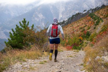 Sırt çantalı erkek koşucu dağda sonbahar maratonu yapıyor.