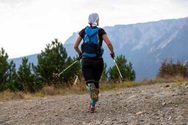 Elinde sırıkla dağ yürüyüşü maratonu yapan kadın sporcu.