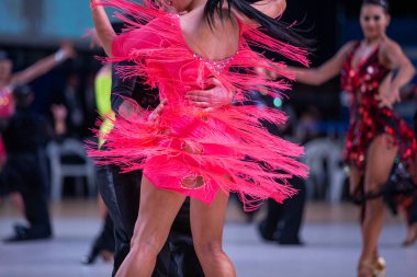 Balo dansçısı çift rakiplerinin arka planında Latin dansı yapıyor.