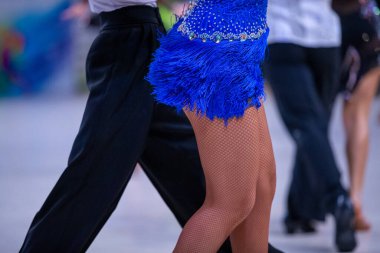 Yakın plan balo salonu çifti, canlı mavi püsküllü elbiseler ve file çoraplara odaklanıyorlar.