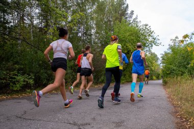 Grup koşucuları sonbahar parkında yolda koşuyor