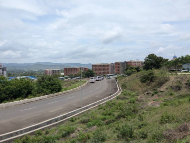 Arka planda yeşil bir yamaç olan bir yol. Yolda hiç araba yok.