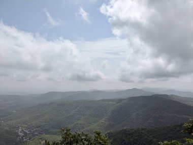 Görkemli tepeler ufuk boyunca uzanır. Yumuşak ışık yoğun bulutların arasından süzülür. Huzurlu bir manzarada anlamlı bulutlar..