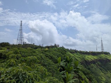 Rajgad Kalesi ve yemyeşil Sahyadri sırasının bulutlu muson yağmurlarının altında arka planda kulesi olan geniş bir manzarası.