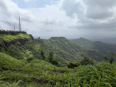 Uçsuz bucaksız yeşil bir vadinin panoramik görüntüsü sarp kayalıkları ve radyo kuleleri ile bulutlu bir muson gününde tepelik bir bölgede yakalandı..