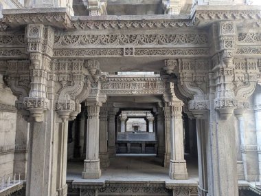 Adalaj Stepwell 'in içini, katmanlı derinlik, dekoratif detaylar ve dengeli tarihi mimari içeren entrika oyulmuş taş sütunlar ve kirişler çerçevelediler..
