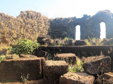 Raigad Kalesi zirvesinde yıkılan taş bloklar ve kalenin kalıntıları, tarihi askeri mimariyi ve yıpranmış dağ yapısını yansıtıyor.