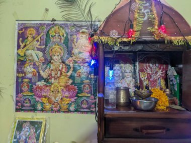 İçeride dua köşesinde Hindu tanrıları çiçek ışıklarını ve ayin malzemelerini gösteriyor.