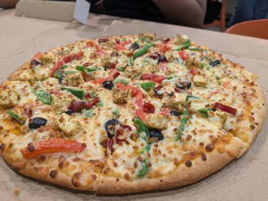 Peynirli, sebzeli ve zeytinli yuvarlak pizza.