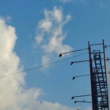 Sokak lambaları ve kablolar dağınık bulutlu mavi bir gökyüzüne yakalanmış..