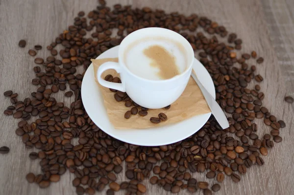 Copa de capuchino y granos de café — Foto de Stock