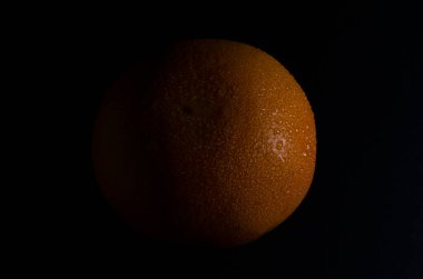 Siyah zemin üzerinde su damlaları olan taze greyfurt