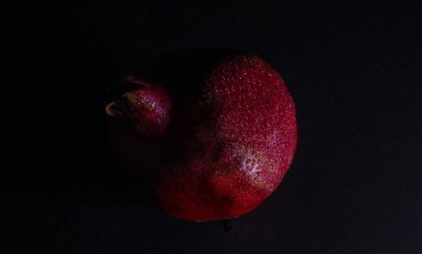 Siyah zemin üzerinde su damlaları olan nar