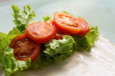 Canlı taze domates dilimleri ve taze marul yaprakları lezzetli ve sağlıklı bir yemek için hazır. Mutfak ilhamı için mükemmel..