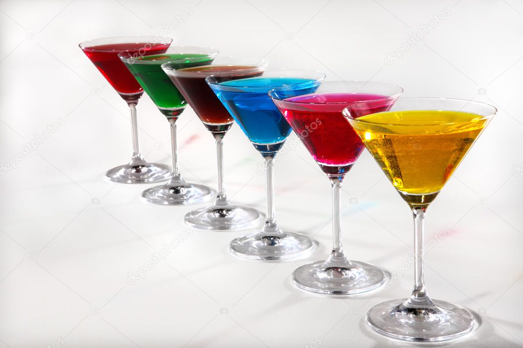 Group of glasses with colored beverages on white background