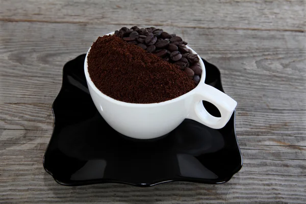 咖啡豆和木制背景上的研磨咖啡的杯子 — 图库照片