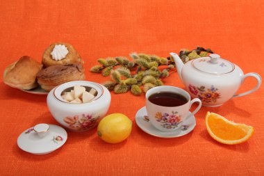 Fincan çay, çaydanlık, fırın, şekerlik, limon, portakal dilimi ve 