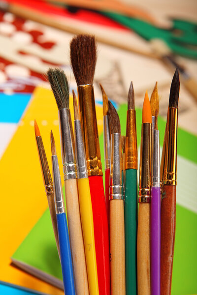 Paint brushes on exercise book background. Selective focus