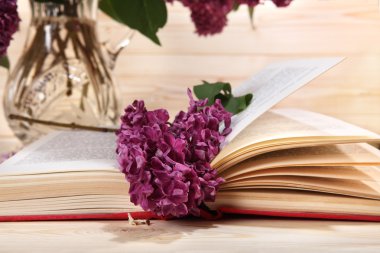 Açık kitap ve demet leylak ahşap arka plan üzerinde