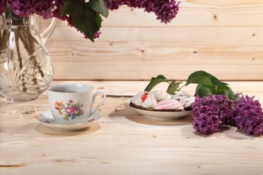 Leylak, fincan çay ve bisküvi ahşap arka plan üzerinde buket