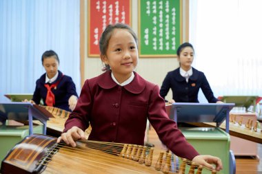 Pyongyang, Kuzey Kore - 12 Ekim 2017: Koreli bir kız, Koreli bir müzik enstrümanı olan Kayageum 'u Pioneers and Schoolkids Sarayı' nda çalıyor.