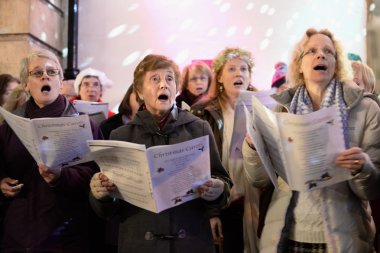 İnsanlar sokaklarda Noel pazarında şarkıları şarkı