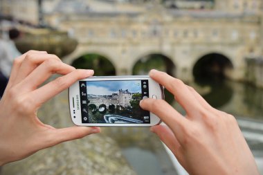 Bir turist Pultney Köprüsü yakalamak için bir akıllı telefon kullanır