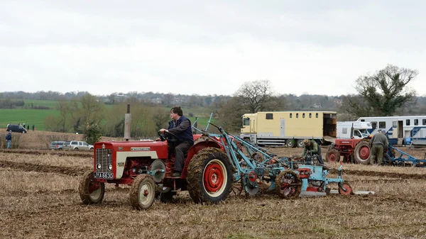 A tractor pulls a plough through a field