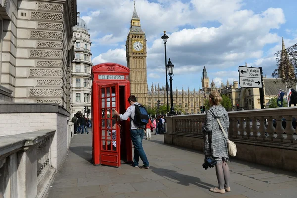 Turystyczny pozuje do zdjęć przez tradycyjne phonebox czerwony w Westminster — Zdjęcie stockowe