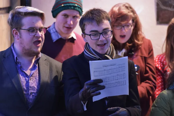 Lidé zpívají koledy na vánočním jarmarku v ulicích — Stock fotografie