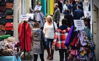 Alışveriş yapanlar şehir merkezindeki bir caddeboyunca yürüyor