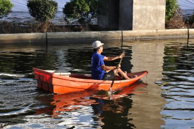Bangkok, Tayland - 18 Kasım 2011: Bir adam sel basmış şehir merkezi yolunda kürek çekiyor. 2011 sel felaketi 815 cana mal oldu ve Tayland genelinde milyonlarca kişi yerlerinden oldu..
