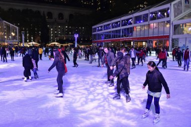 New York City, ABD - 12 Kasım 2018: İnsanlar Manhattan 'daki Bryant Parkı' nda buzun üzerinde mor kar taneleri gibi hafif bir projeksiyonla açık hava buz pateni pistinde kayıyorlar.