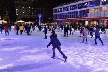 New York City, ABD - 12 Kasım 2018: İnsanlar Manhattan 'daki Bryant Parkı' nda buzun üzerinde mor kar taneleri gibi hafif bir projeksiyonla açık hava buz pateni pistinde kayıyorlar.