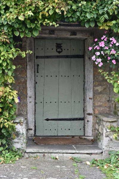 Přední Dveře Starého Anglického Domu Obklopeného Listnatými Rostlinami — Stock fotografie