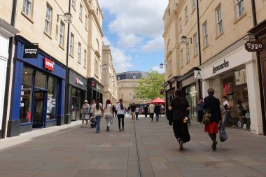 28 Mayıs 2025 'te Bath, İngiltere' de güneşli bir günde turistler ve yerliler şehir merkezindeki bir alışveriş caddesi boyunca yürürler. Bath, her yıl 5 milyon ziyaretçiyle İngiltere 'nin en popüler turist merkezlerinden biri..