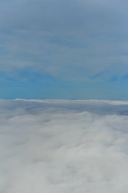 Mavi gökyüzü, beyaz kabarık bulutlar yüksek irtifada görünüyor.