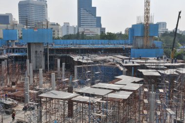 İnşaat işçileri, 22 Aralık 2010 'da Bangkok, Tayland' da büyük bir kentsel kalkınma sahasında karmaşık inşaat ve çelik inşaat inşaat inşaat inşaat inşaat inşaat inşaat demirleri inşa ediyorlar. Manzara, modern metropol genişlemesi için gereken karmaşık altyapıyı vurguluyor.