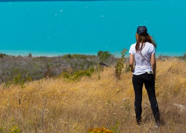 Arkadan ayakta ve turkuaz la doğru bakan kadın görünüşü