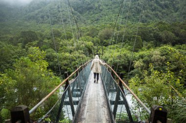 Kadında Suspended köprüde yürürken yağmurluk 