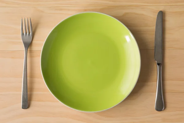 Assiette verte avec fourchette et couteau — Photo