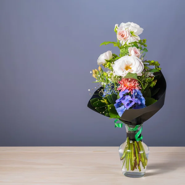 Bos bloemen in een glasvaas op houten tafel — Stockfoto