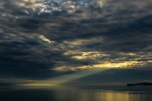 Sun's rays make their way through the hole in clouds — Stock Photo, Image