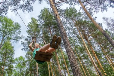 Kız ormanda bir salıncak üzerinde sallanan