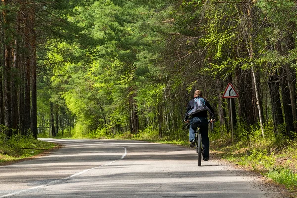 cyclist rides along the road in the forest