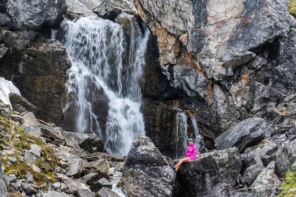 Mädchen sitzt auf einem Stein unter dem Wasserfall — Stockfoto