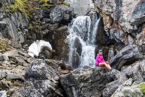 Mädchen sitzt auf einem Stein unter dem Wasserfall — Stockfoto