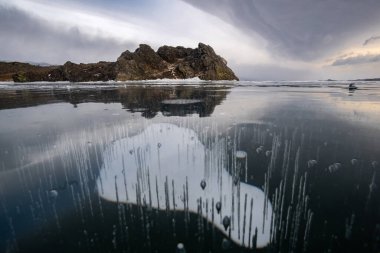 Winter landscape on Lake Baikal with methane bubbles in the foreground clipart