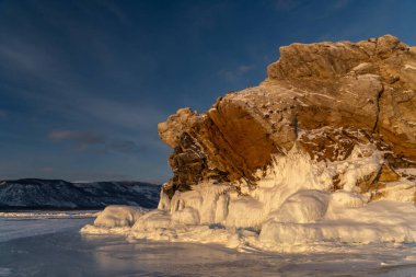 Baykal Gölü kıyısındaki kayalar batan güneşle aydınlanıyor.