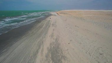 Mavi okyanus dalgalarının havadan görünüşü altın bir kumsalda yuvarlanıyor. Sakin ve rahatlatıcı bir ruh hali.